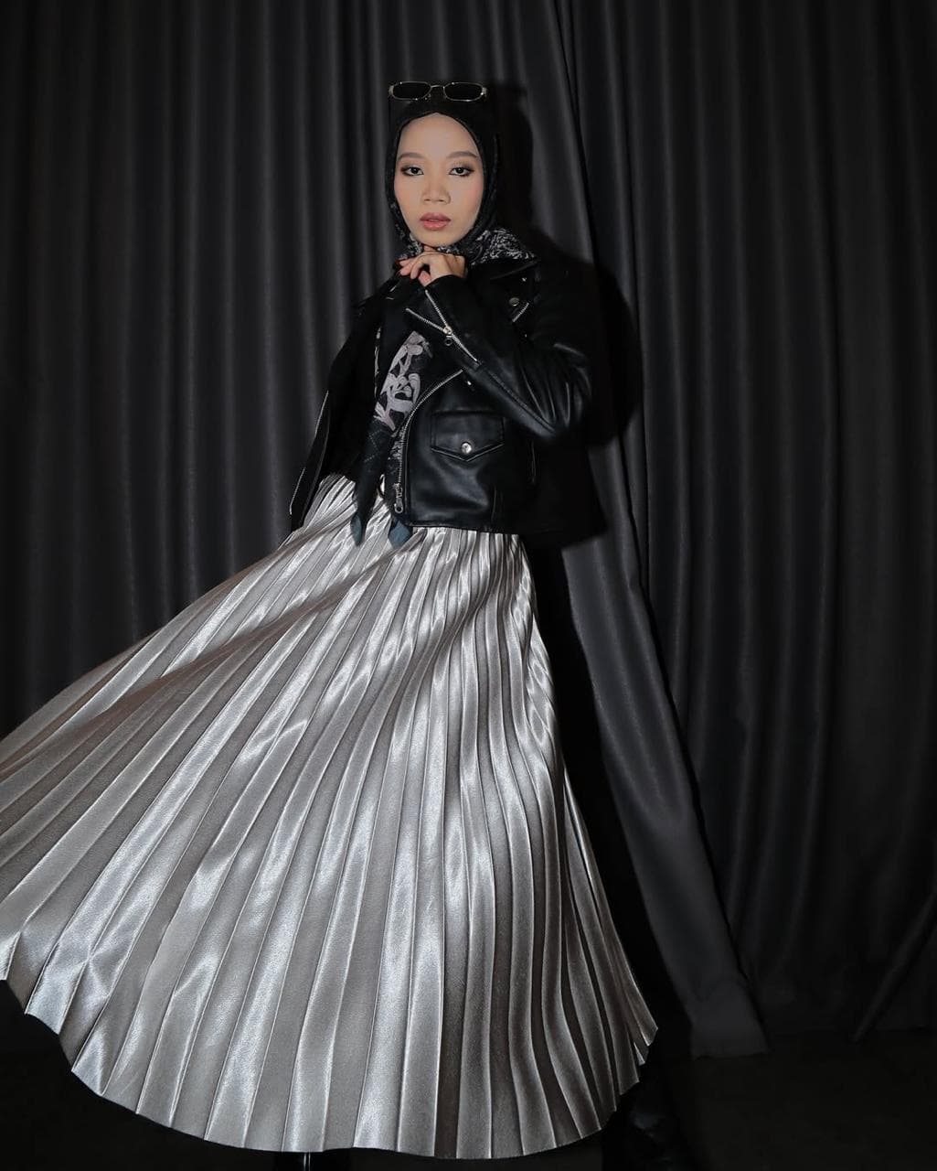 Model runway fashion dengan jaket kulit dan rok silver pleated